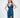 A model poses in a sleek, deep blue satin dress with a plunging neckline and a thigh-high slit.