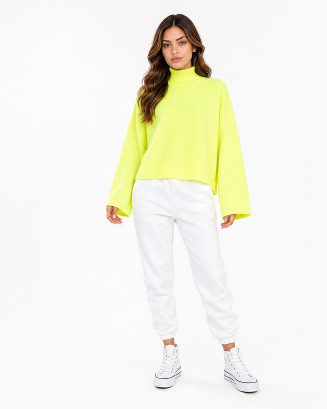 A model wearing a bright neon yellow turtleneck top paired with white joggers and white sneakers.