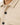 Close-up of a textured beige top featuring a patterned fabric, black buttons, and a classic collar design.