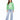 A woman stands wearing a green sweatshirt with white text, paired with light blue wide-leg jeans and white sneakers.