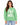 A woman wearing a green sweatshirt with bold white lettering and a casual style, paired with light jeans.