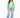 A woman stands wearing a green sweatshirt with bold white lettering, paired with light blue wide-leg jeans and white...