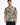 A man wearing a short-sleeve, patterned shirt with abstract black and beige designs, standing against a white backgro...