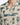 Close-up of a short-sleeve shirt featuring a beige fabric with green abstract patterns and button details.