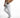 Side view of Luka white jeans featuring moto-ribbed knees, distressed detailing, and a streetwear aesthetic.