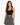 A woman with long, wavy hair wears a fitted black ribbed crop top paired with a patterned black and white skirt.