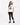 A woman stands wearing a white graphic tee with a zebra print design, paired with black leggings and sneakers.