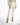 Maisie high-waisted white trousers paired with a beige blouse and black pearl-studded heels.