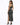 A woman in a sparkling black two-piece outfit with a high slit, paired with black heels, poses from the back.