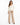 A woman stands confidently in a fitted cream jacket paired with beige wide-leg trousers and black heels.