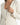 A close-up of a light-colored jacket featuring a deep V-neckline and elegant button details on the sleeves.