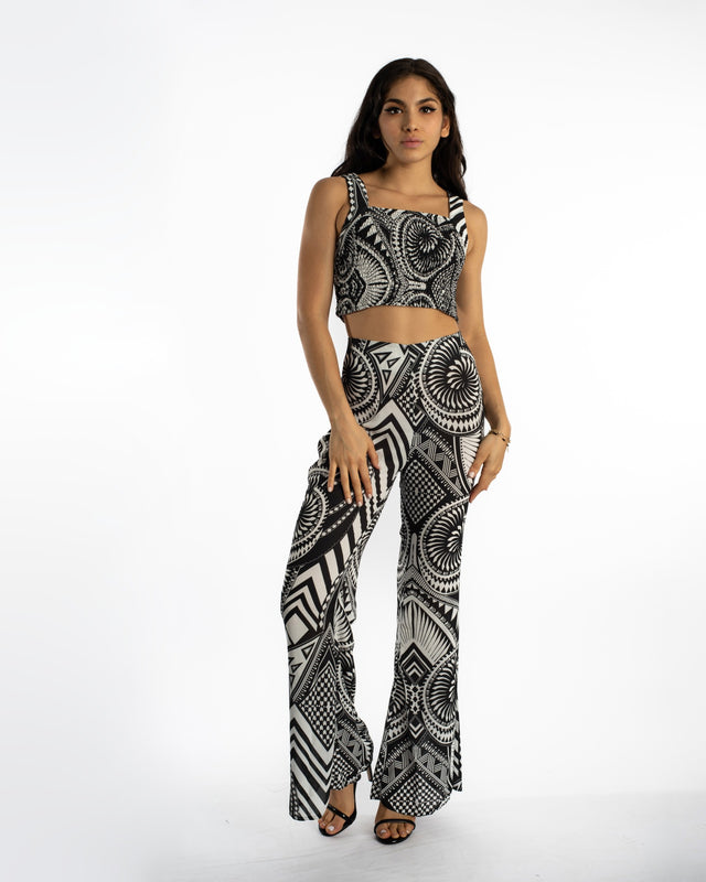 Model wearing high-waisted wide leg Marlee pants in a black and white geometric tribal print with a matching crop top.
