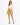 A woman stands confidently in a cream long-sleeve top paired with a mustard mini skirt and black strappy heels.