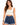 A model poses in a fitted, light-colored crop top paired with high-waisted denim shorts.