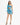 A model poses in a vibrant blue and teal one-shoulder dress with a fitted silhouette and ruched detailing.