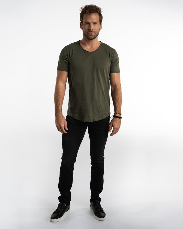 Model in Mason slim straight black jeans with subtle distressing, olive t-shirt, and black sneakers on white backdrop.