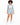 A woman with curly hair wears a light blue blazer and matching shorts, paired with a white crop top and sneakers.
