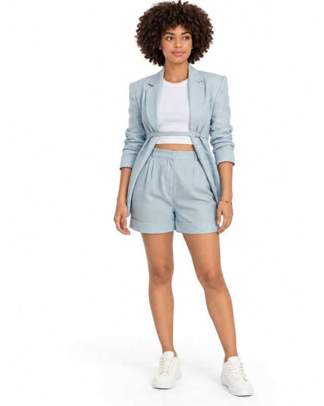 A model wearing light blue tailored shorts paired with a matching blazer and white sneakers.