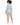 A woman with curly hair wears a light blue blazer and matching shorts, paired with white sneakers.
