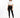 A woman with curly hair stands confidently in black leggings and a cropped white top, paired with stylish boots.