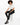 A person with curly hair sits on a white cube, wearing black leggings and a cropped white shirt with stylish sneakers.