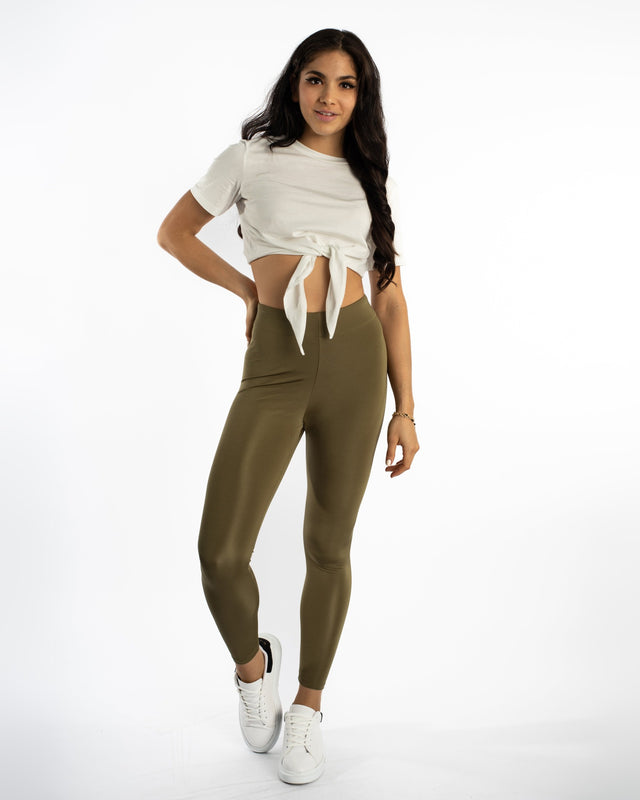 Model in olive green Emory high-waisted leggings by Carbon with a sculpting fit and a white tie-front crop top.