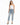 A woman stands confidently in light blue distressed jeans, paired with a fitted white top and black heels.