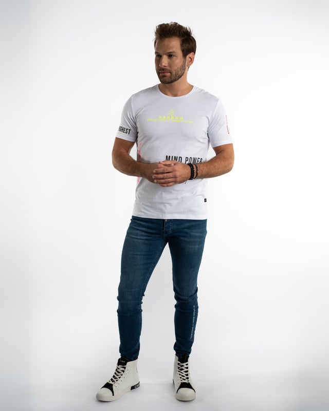 Man in white Mind Power graphic streetwear t-shirt and blue jeans against a white background.