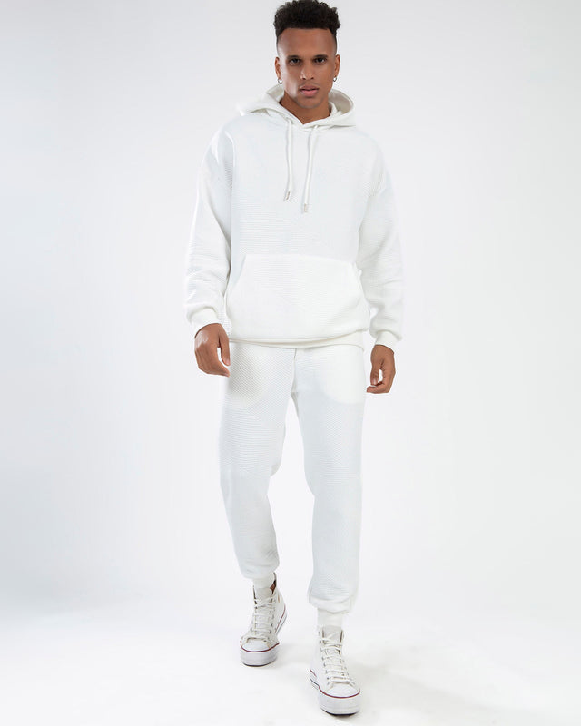Man in white diagonal ribbed knit Eric Hoodie Set with matching streetwear joggers and high-top sneakers.