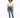 A model poses in a cropped white top and fitted blue jeans, paired with white sneakers against a plain background.