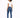 A model with curly hair wears a fitted white top and blue skinny jeans, paired with white sneakers, facing away.