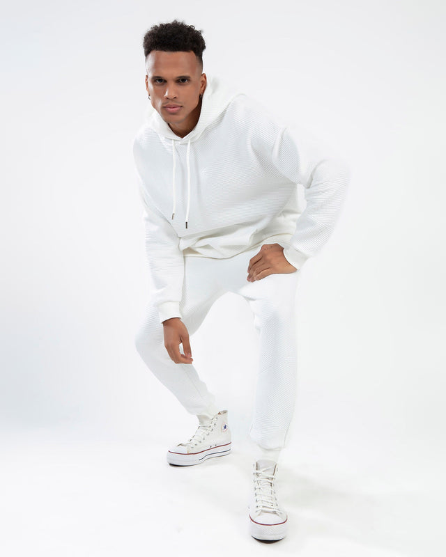 Man wearing Eric white two-piece streetwear set with textured ribbed hoodie and matching joggers for a clean aesthetic.
