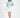 Model wearing the More and Less teal knit cropped sweatshirt and a white mini skirt against a white background.