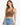 A woman with long hair wears a fitted brown ribbed crop top paired with high-waisted distressed denim shorts.