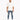 A man stands confidently in distressed blue jeans, paired with a loose-fitting white t-shirt and white sneakers.