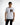A young man wearing a white t-shirt with graphic text and a photo print, paired with black jeans.