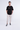 Model wearing a black Survive graphic t-shirt with SUNSHINE text, beige cargo pants, and black and white sneakers.
