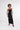 Model in Ivy black shimmer maxi dress with side cutouts and spaghetti straps against a white background.