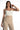 Model wearing the white Emmie Strapless Bustier, a structured corset-style crop top paired with beige trousers.