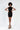 Model wearing Nevaeh black velvet mini dress with high neck and side lace-up cutouts against white background.
