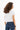 Back view of the white Leah Ribbed Crop Top with cuffed sleeves, paired with high-waisted blue jeans.