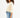 Side view of woman in Clay asymmetrical one shoulder sweatshirt and distressed denim streetwear shorts.