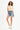 Model wearing the beige Leah Ribbed Crop Top with high-waisted distressed denim shorts and white sneakers.