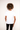 Back view of a model wearing the white Magnifique graphic tee in a minimalist streetwear style with a relaxed fit.