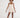 Model wears the beige Scarlet Romper, featuring spaghetti straps and a cross-over bodice with a ruffled skirt.