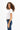 Side view of the Leah White Ribbed Crop Top paired with dark wash jeans on a model with curly hair.