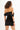 Back view of a woman wearing the Kelly black velvet mini dress with an off-the-shoulder neckline and bodycon fit.