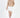 Serena beige cable knit turtleneck sweater in an oversized fit paired with a white mini skirt.