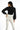 Rear view of a model wearing the Carbon Zuri Knit Top with long puff sleeves and white high-waisted trousers.