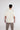 Back view of a man wearing an oversized cream Fine Arts graphic streetwear shirt with relaxed fit cotton sleeves.